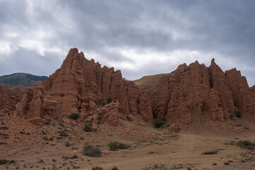 Fototapeta premium Beautiful red clay mountains eroded on wind. Red mountains or red canyon on the way from Assy plateau to Bartogai reservoir. Mountain canyon landscape.