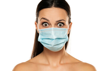 Beautiful shirtless caucasian young woman with disposable face mask. Protection versus viruses and infection. Studio portrait, panic concept