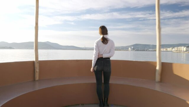 Dolly in shot, of a girl gazing upon the sea. Shot during golden hour in Volos, Greece.
