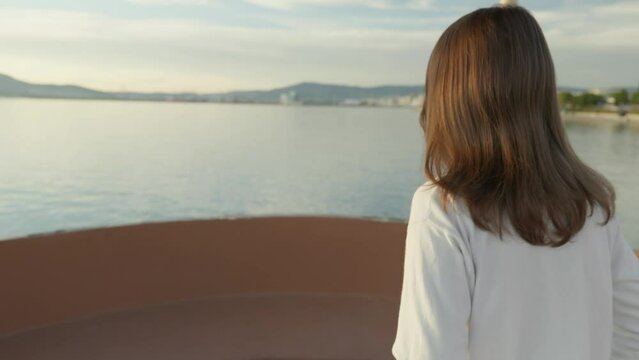 Reveal shot of a girl walking during golden hour. Flares and the setting sun shown in the end.