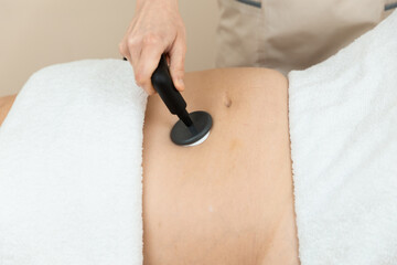 Woman receiving radiofrequency stimulation treatment for faster recovery like for inflammations, pelvic floor, scarring