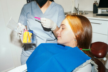 Orthodontist preparing brace rubber bands with a teenage girl. 