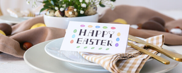 Beautiful table setting with Easter greeting card, closeup