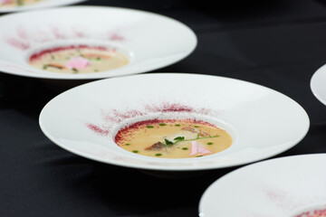 fish cream soup with salmon, cheese and herbs in white soup bowls