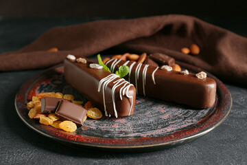 Plate with delicious chocolate cakes, almonds and raisins on dark background