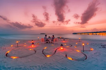 Fototapeten Amazing romantic dinner on the beach with candles and flowers under sunset sky. Romance and love, luxury destination dinning, exotic table setup with sea view. Honeymoon celebration anniversary design © icemanphotos