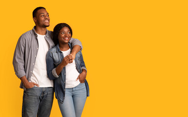 Young happy black couple embracing and looking at copy space with interest