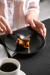 Obraz na płótnie Canvas Woman eating tasty Basque burnt cheesecake at table
