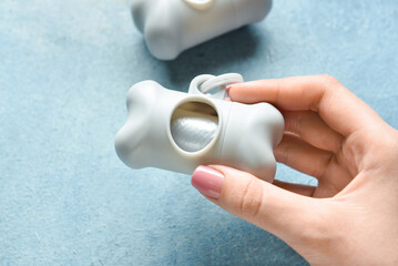 Female hand with pet waste bags on blue background, closeup