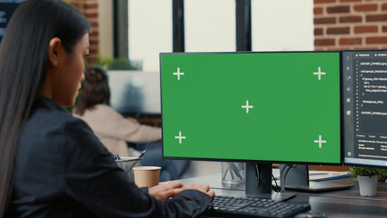Focus on computer screen with green screen chroma key mockup in front of asian programer writing...