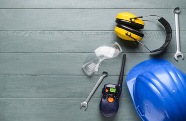 Safety equipment with builder's tools and radio transmitter on wooden background
