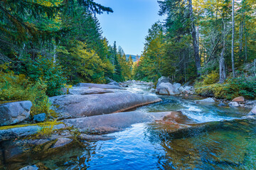 Huge smooth boulders honed by ancient glaciers and flows of the Ammonoosuk mountain river near a waterfall in the foothills of Mount Washington in the White Mountain National Forest, New Hampshire