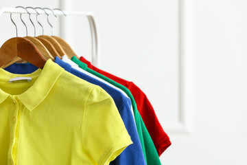 Obraz premium Rack with clean t-shirts near light wall
