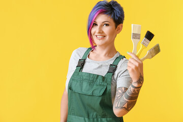 Female painter with brushes on yellow background