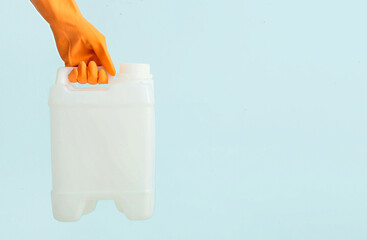 Female hand in rubber gloves holding canister on color background