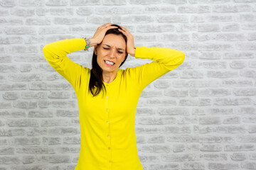 Woman wearing casual yellow sweater suffering from headache desperate and stressed because pain and migraine. hands on head. suffering migraine. 