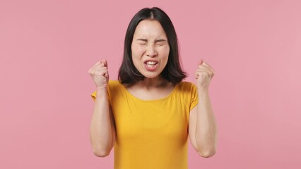 Displeased irritated angry young woman of Asian ethnicity 20s wears yellow t-shirt closed eyes cover ears do not want to listen scream isolated on plain pastel light pink background studio portrait - Powered by Adobe
