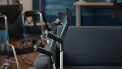 Fototapeta premium Crutches on empty couch in living room to give mobility support to people with chronic disability or injury. Walking sticks helping with transportation and physical accessibility. Walk crutch
