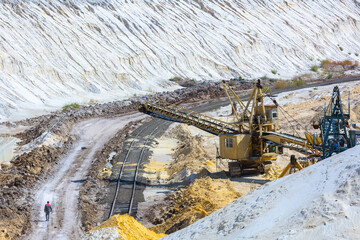 Quarry extraction porcelain clay(kaolin) and quartz sand in the open pit mine. Powerful industrial belt conveyor loader near the access railway track at the deposit opening site.