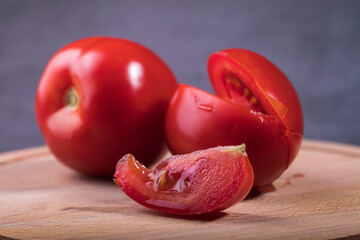 There are red tomatoes on the table and a slice is cut off from the tomato. - 487959486