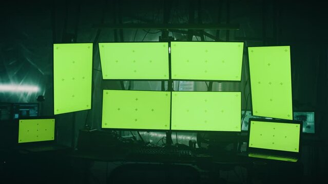 Zoom in view of hi tech computer monitors and netbooks with green screens ready for hacker attack in dark room