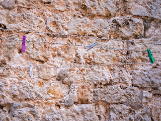 clothespins on a rope on a background of a stone wall