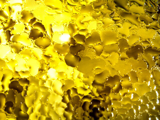 yellow water drops on glass surface, background or texture
