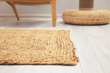 Wicker carpet on light wooden floor in room interior, closeup