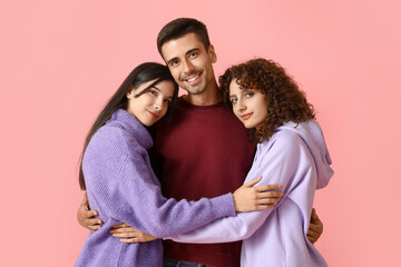 Man and two beautiful women on color background. Polyamory concept