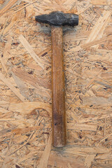old hammer with a wooden handle. antiques. hand tool for driving nails. wooden background. top view.