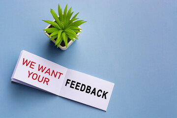 Text on notepad with reading glasses and potted plant on blue background