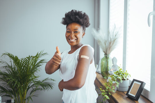 Portrait Of African American Woman Showing Her Arm With Band Aid After Coronavirus Covid-19 Vaccine Injection. Businesswoman Showing Her Arm After Getting Vaccinated In The Office.