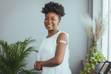 Vaccinated african american young woman showing arm after covid-19 vaccine injection, standing on...