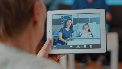 Retired woman talking to daughter and child on remote video call, holding digital tablet....