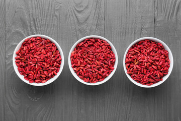 Bowls with dried barberries on wooden background