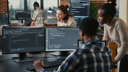 Mixed team of artificial intelligence cloud programers talking about programming in front of...