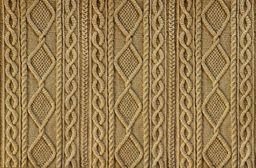 Beige background knitted fabric with a pattern. Knitted Arans close-up