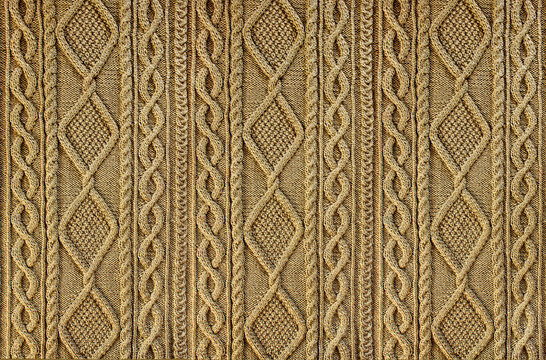 Beige background knitted fabric with a pattern. Knitted Arans close-up