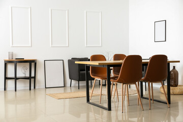 Interior of light dining room with table and black armchairs