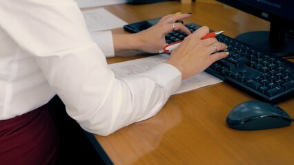 Office worker during work. Woman fills out a statement on the keyboard. - obrazy, fototapety, plakaty