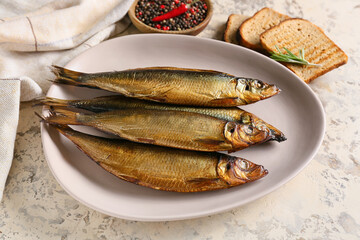 Plate with smoked herring fishes on beige background