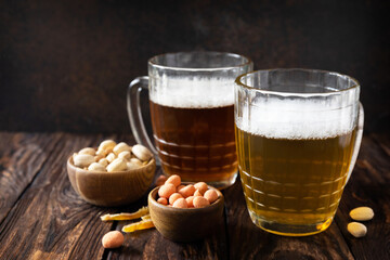 Alcohol drinkpint of lager and pint of stout, craft beer. Two Glass of Beer with foam and snacks on a wooden rustic background. Traditional German wheat beer. Copy space.
