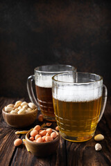 Alcohol drink pint of lager and pint of stout, craft beer. Two Glass of Beer with foam and snacks on a wooden rustic background. Traditional German wheat beer. Copy space.