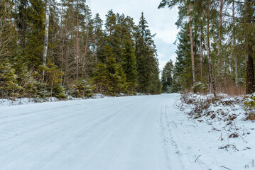 Empty snow covered road in winter landscape.Snowy Road through a forest Landscape in Winter Cloudy Day.