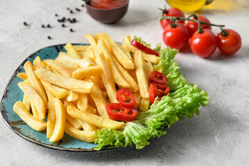 Plate with tasty french fries on light background