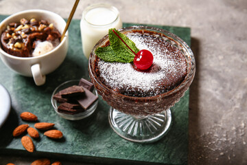 Glass bowl with tasty chocolate brownie on grey background