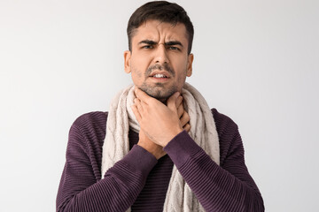 Ill young man with sore throat on white background