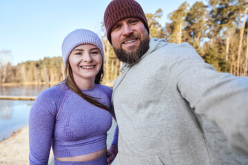 Adult caucasian couple talking a selfie during running in winter