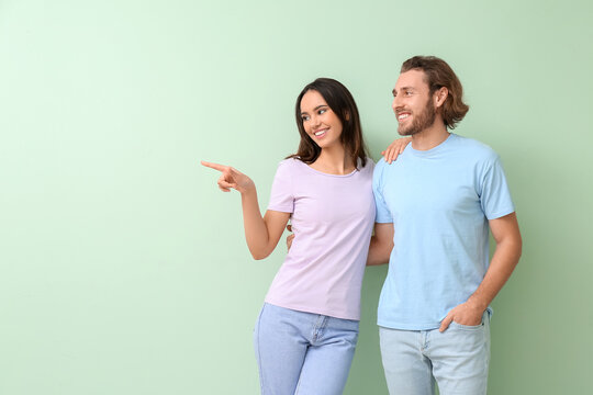 Young couple in stylish t-shirts on green background
