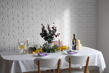 Dining table with beautiful setting and candles near brick wall